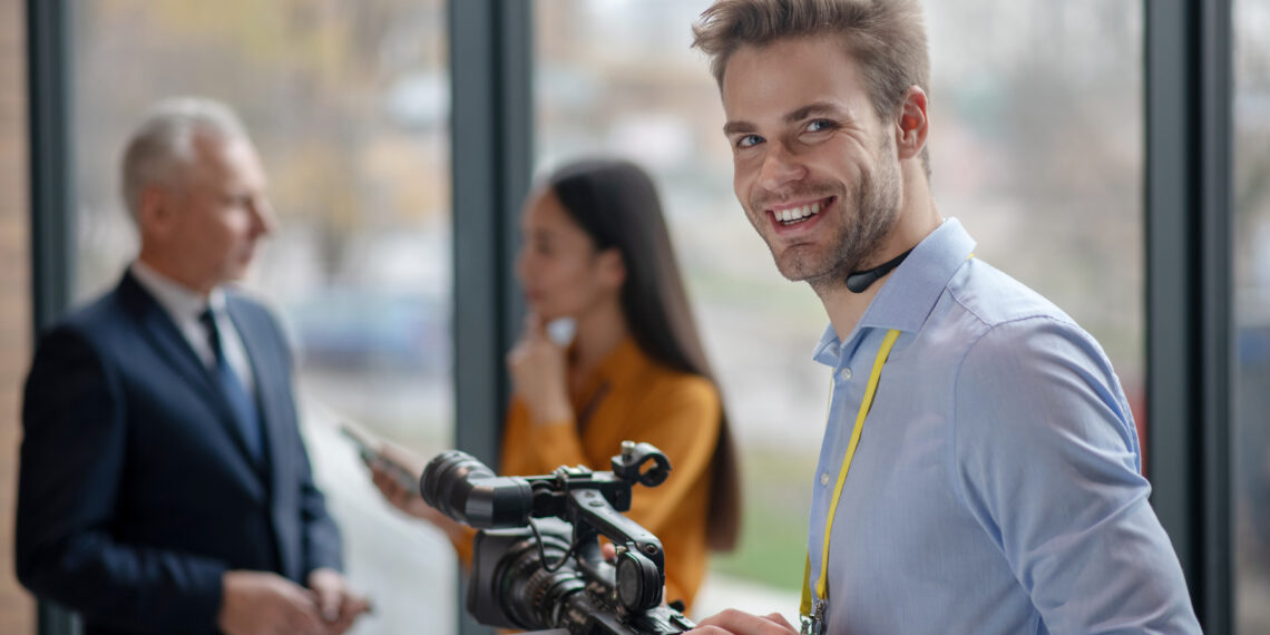 Good results. Male young operator with video camera looking satisfied with his work