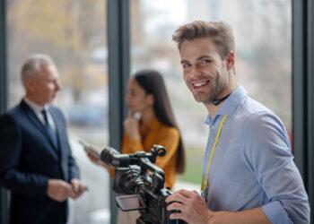 Good results. Male young operator with video camera looking satisfied with his work